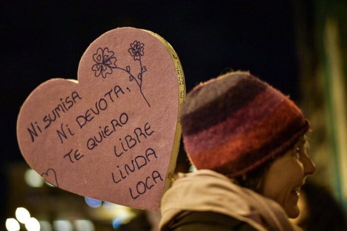 A demonstrator raises a heart shaped cardboard sign reading ''Not submissive. Not devotee. I want you to be free, beautiful and crazy.'' Photo: Alvaro Barrientos / Associated Press