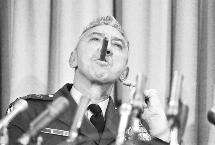 Lt. Gen. William R. Peers, head of the Army panel flying to Vietnam to investigate the initial probe into the alleged My Lai massacre, sights along his cigar during a preflight news conference in 1969 in the Pentagon. Photo: Associated Press