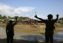 At the Border’s Cloudy Edge, Rohingya Insist They Will Stay Bangladeshi border guard personnel gesture to Rohingya stuck in "no man's land" on Aug. 27, 2017, as they tell them not to cross in Tombru. Photo: Mushfiqul Alam / Associated Press