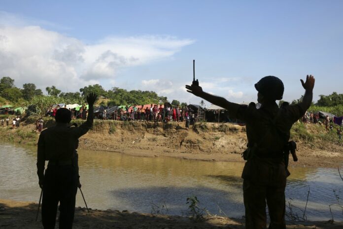 Bangladeshi border guard personnel gesture to Rohingya stuck in 