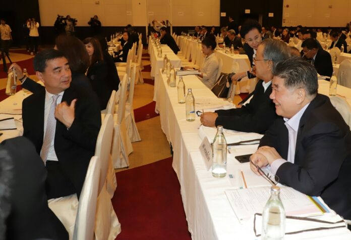 Rival revelry? Democrat Party chairman Abhisit Vejjajiva and Pheu Thai sec-gen Phumtham Wechayachai chat Tuesday at an Election Commission briefing in Bangkok.