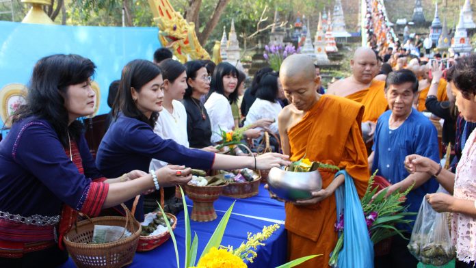Ethnic groups give offerings of khao tom mad to monks Thursday at Wat Nanong in Ratchaburi.