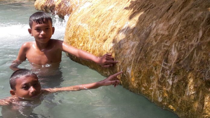 Children point Monday to marks left by guests on the edge of Emerald Pool in Krabi province. Photo: Matichon Children point Monday to marks left by guests on the edge of Emerald Pool in Krabi province. Photo: Matichon
