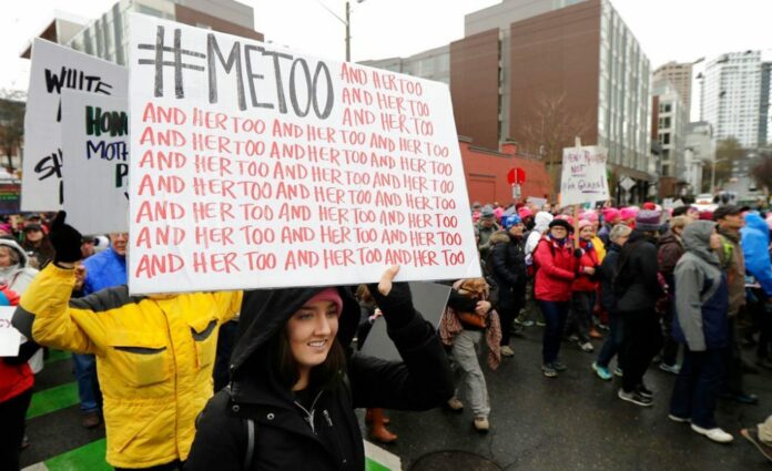 FILE - In this Saturday, Jan. 20, 2018 file photo, a marcher carries a sign with the popular Twitter hashtag #MeToo used by people speaking out against sexual harassment as she takes part in a Women's March in Seattle, on the anniversary of President Donald Trump's inauguration. (AP Photo/Ted S. Warren)