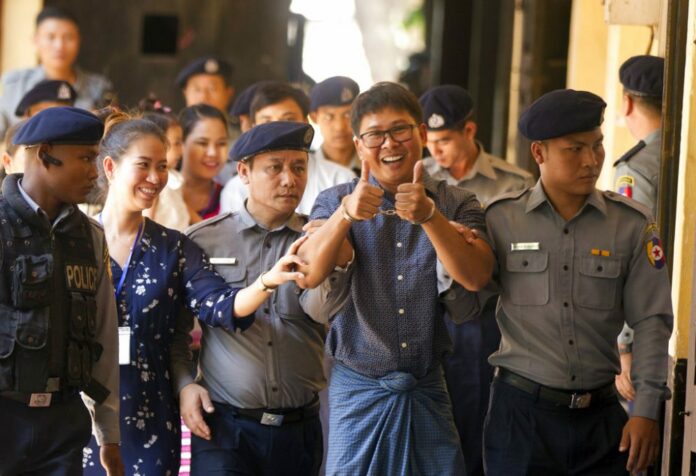 Reuters journalist Wa Lone, center, walks along with his wife Pan Ei Mon, second left, as he is escorted by police upon arrival at his trial Wednesday, April.11, 2018, Yangon, Myanmar. (AP Photo/Thein Zaw)