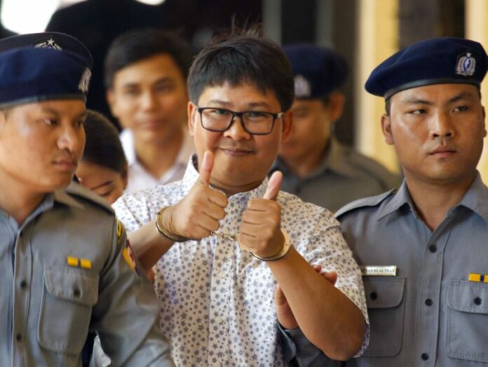 Reuters journalist Wa Lone, center, thumbs up as he is escorted by police upon arrival at the court for trial in Yangon. Photo: Thein Zaw / Associated Press