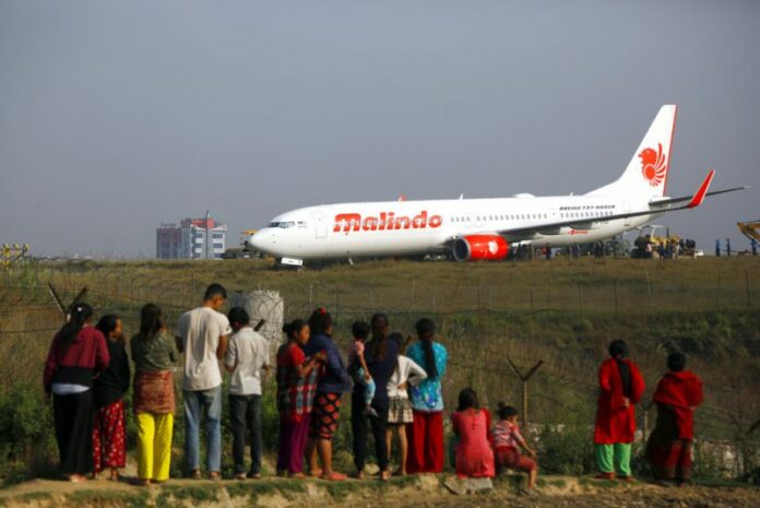 People watch a Malindo Air passenger plane after it skidded to the grassy area at the end of runway in Tribhuwan International Airport in Kathmandu, Nepal, Friday. Photo: Niranjan Shrestha / Associated Press