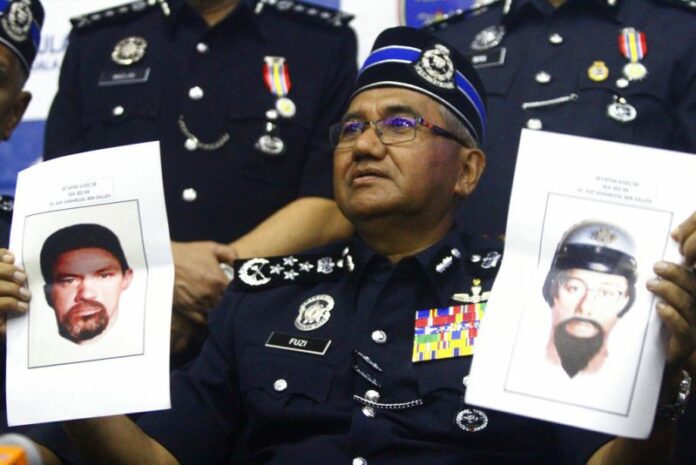 Inspector General of Royal Malaysian Police Mohamad Fuzi Harun shows off two images of suspects of killing of a Palestinian man. Photo: Associated Press