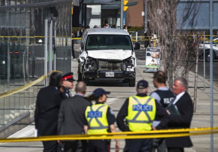 Police are seen near a damaged van after a van mounted a sidewalk crashing into pedestrians in Toronto on Monday, April 23, 2018. Photo: Aaron Vincent Elkaim / The Canadian Press via AP