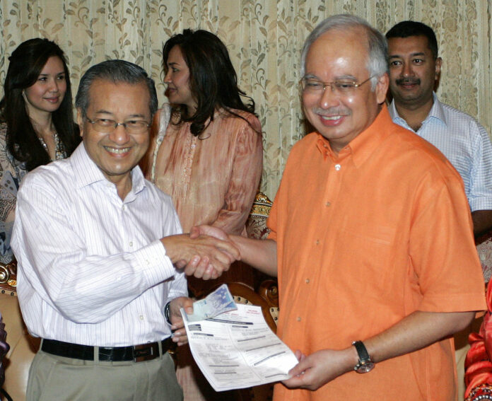 Malaysian Prime Minister Najib Razak, right, receives the party form from former Prime Minister Mahathir Mohamad, left, as Mahathir rejoin United Malays National Organization's (UMNO) in 2009 in Putrajaya, Malaysia. Photo: Lai Seng Sin / Associated Press
