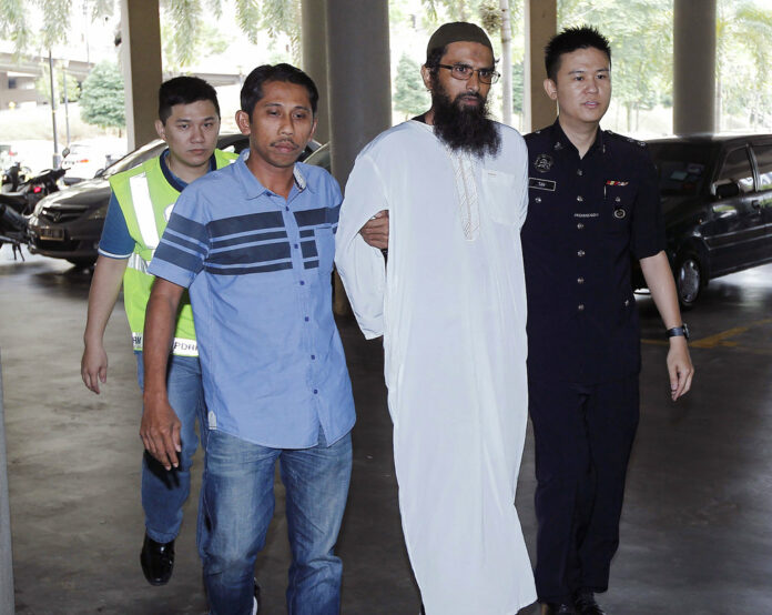 Danish national Salah Salem Saleh Sulaiman, second from right, escorted by police, arrives Monday at a court house in Kuala Lumpur, Malaysia. Photo: Associated Press