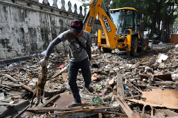 A man carries a cat April 25 out of the wreckage of Pom Mahakan.