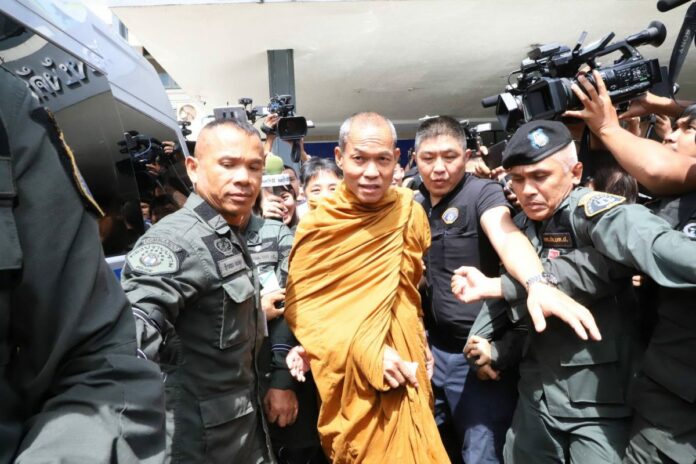 Police escort Buddha Issara out of the Crime Suppression Division on Thursday afternoon.