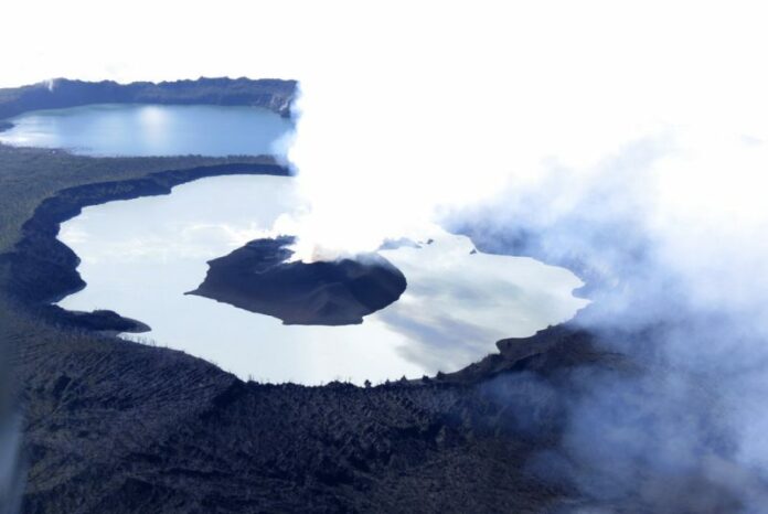 steam rises from the volcanic cone that has formed in Lake Vui near the summit of Ambae Island, Vanuatu. Photo: Brad Scott / Associated Press