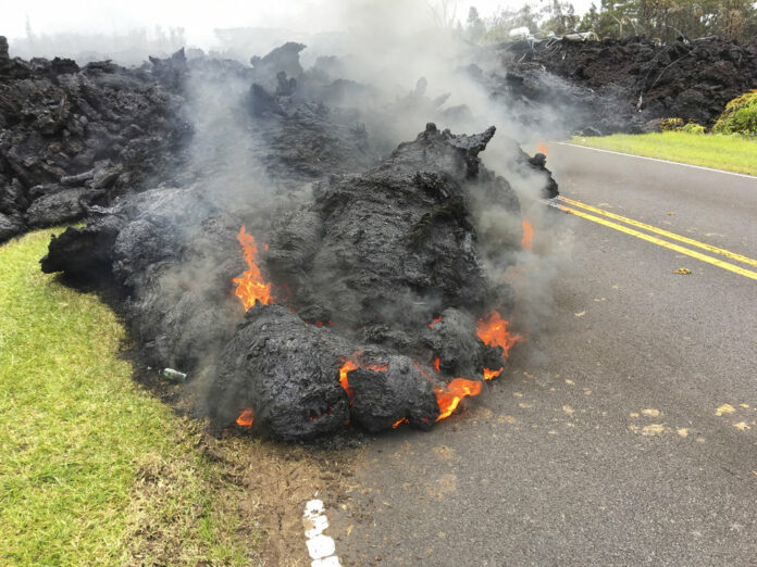 Lava from the Kilauea volcano moves across the road Saturday in the Leilani Estates in Pahoa, Hawaii. Photo: Marco Garcia / Associated Press