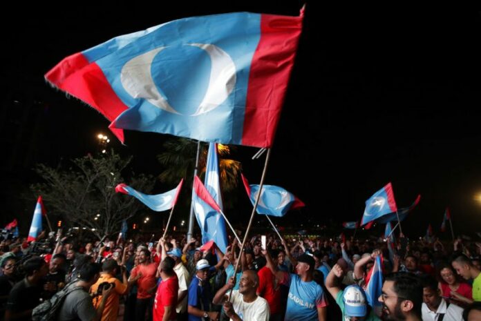 Opposition party supporters cheer and wave their party flags after Mahathir Mohamad claims the opposition party wins the General Election, broadcast on a large screen at a field in Kuala Lumpur, Malaysia, Wednesday, May 9, 2018. Photo: Andy Wong / Associated Press