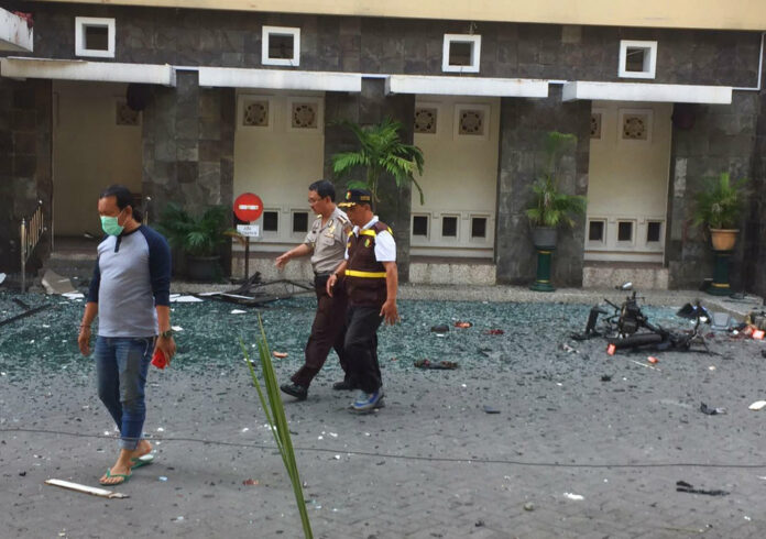 Officers walk past debris at Santa Maria church where an explosion went off Sunday in Surabaya, East Java, Indonesia. Photo: Trisnadi / Associated Press