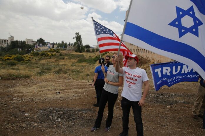 Israelis hold American and Israeli flags with the new U.S. embassy Monday in the background in Jerusalem. Photo: Sebastian Scheiner / Associated Press