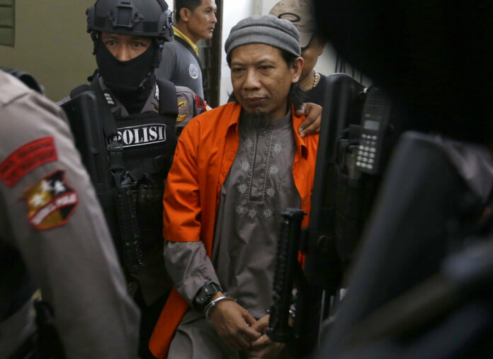 Islamic cleric Aman Abdurrahman, center, is escorted by police officers upon arrival for his trial at South Jakarta District Court on Friday in Jakarta, Indonesia. Photo: Tatan Syuflana / Associated Press