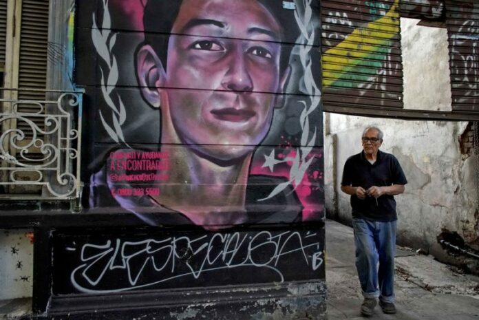 A man walks by a mural of Enzo Vallejos, a 16-year-old teenager who has been missing since last year, in Buenos Aires, Argentina. Photo: Victor R. Caivano / Associated Press