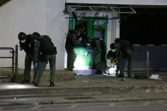 Forensic officers search a bombed ATM for evidence Sunday night in Pattani