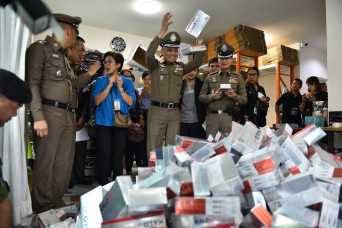 Police Lt. Gen. Weerachai Songmetta tosses a pile of Kalow diet pills seized by police Monday.