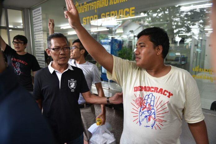 Protest leader Sirawith Seritiwat flashes the anti-junta 'three fingers salute' at Chanasongkram Police Station today