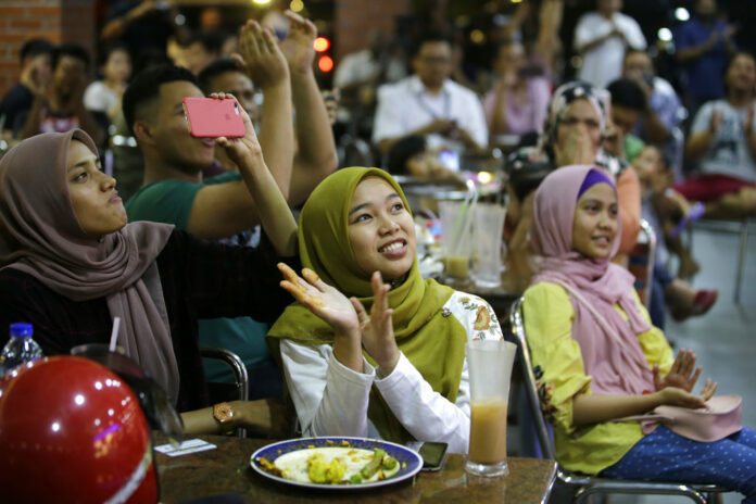 People at a restaurant applaud as they watch TV showing former strongman Mahathir Mohamad sworn in as the new Malaysian Prime Minister in Kuala Lumpur, Malaysia on Thursday. Photo: Aaron Favila / Associated Press