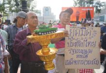 Call Elections or We’ll March on Govt House: Protest (Video) Protesters hold a model of a military tank atop a representation of the constitution during a Saturday pro-democracy at Thammasat University in Bangkok. It reads, 'Dark age of democracy, constitution under authoritarian (tank).'