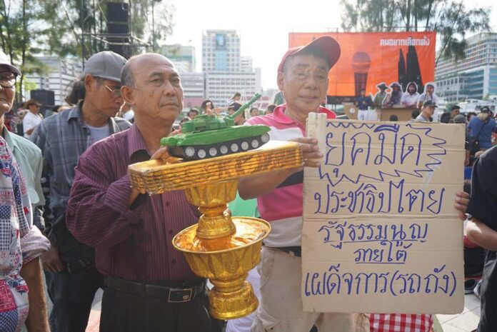 Protesters hold a model of a military tank atop a representation of the constitution during a Saturday pro-democracy at Thammasat University in Bangkok. It reads, 'Dark age of democracy, constitution under authoritarian (tank).'