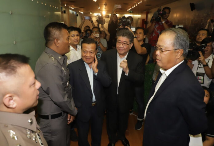 Police speak to Pheu Thai Party secretary general Phumtham Wechayachai before the party held a news conference Thursday where they criticized the military regime's failures ahead of the four-year coup anniversary at party headquarters in Bangkok. Photo: Matichon