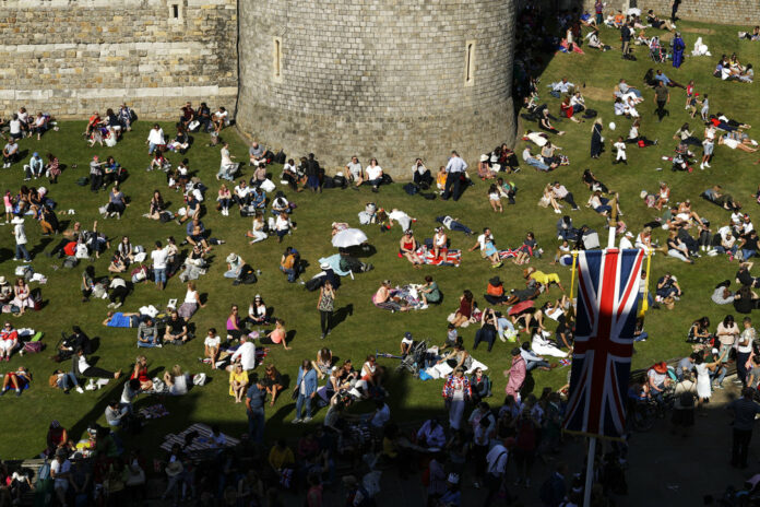 People relax on a grassy bank outside Windsor Castle after Prince Harry and Meghan Markle's wedding ceremony at St. George's Chapel in Windsor, England, on Saturday. Photo: Matt Dunham / Associated Press