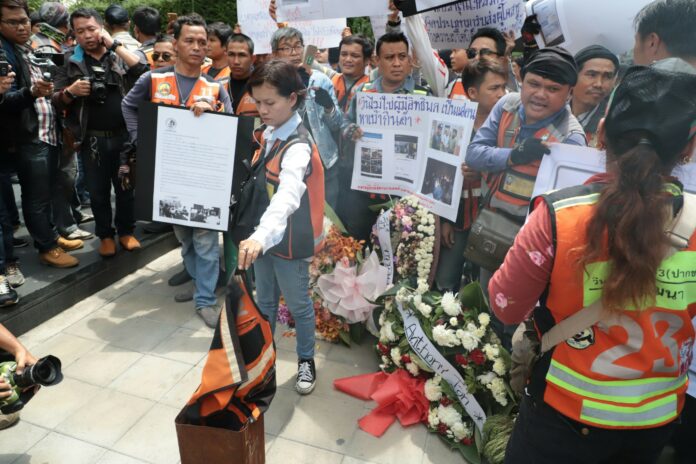 Motorcycle taxis Thursday burn a vest uniform at a protest in front of Grab’s Bangkok headquarters.