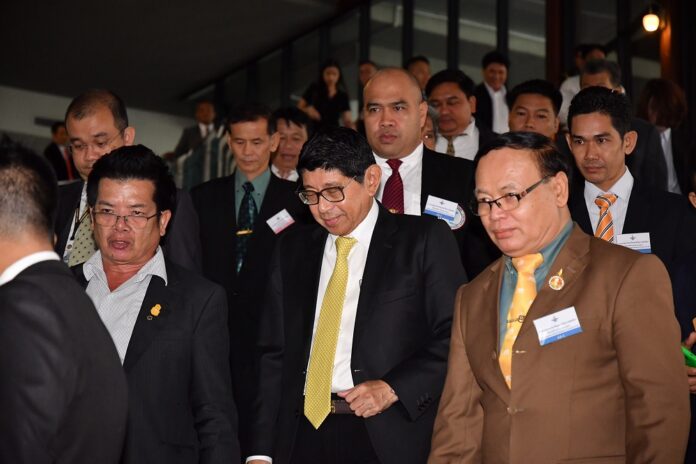 Deputy Prime Minister Wissanu Krue-ngam, center, emerges from a meeting with political parties in June in Bangkok, flanked by meeting participants.