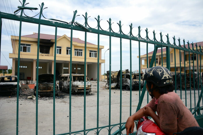 A motorist looks at charred vehicles burned by protesters at a fire and police station Tuesday in the south central province of Binh Thuan, Vietnam. Photo: Associated Press A motorist looks at charred vehicles burned by protesters at a fire and police station Tuesday in the south central province of Binh Thuan, Vietnam. Photo: Associated Press