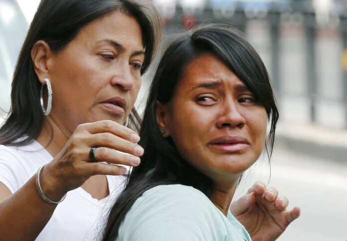 Barbara Barca, right, a survivor of the stampede at a crowded nightclub, cries as she leaves police headquarters in Caracas, Venezuela, Saturday, June 16, 2018. Photo: Ariana Cubillos / Associated Press