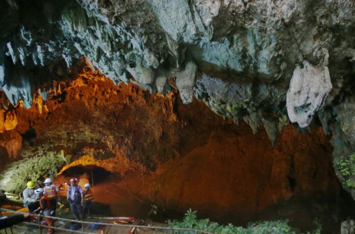 Rescue personnel on June 28 walk out of the entrance to a cave complex where it's believed that 12 soccer team members and their coach went missing. Photo: Sakchai Lalit / Associated Press