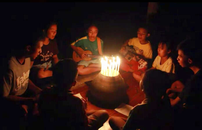 In this image from video made available on Friday, June 29, 2018, a group of young children sit around candles and play a song at a school in Buriram, eastern Thailand, in support for the missing soccer team and their coach in a flooded cave in the north. Photo: Lek Nai Tung Kwang school via AP