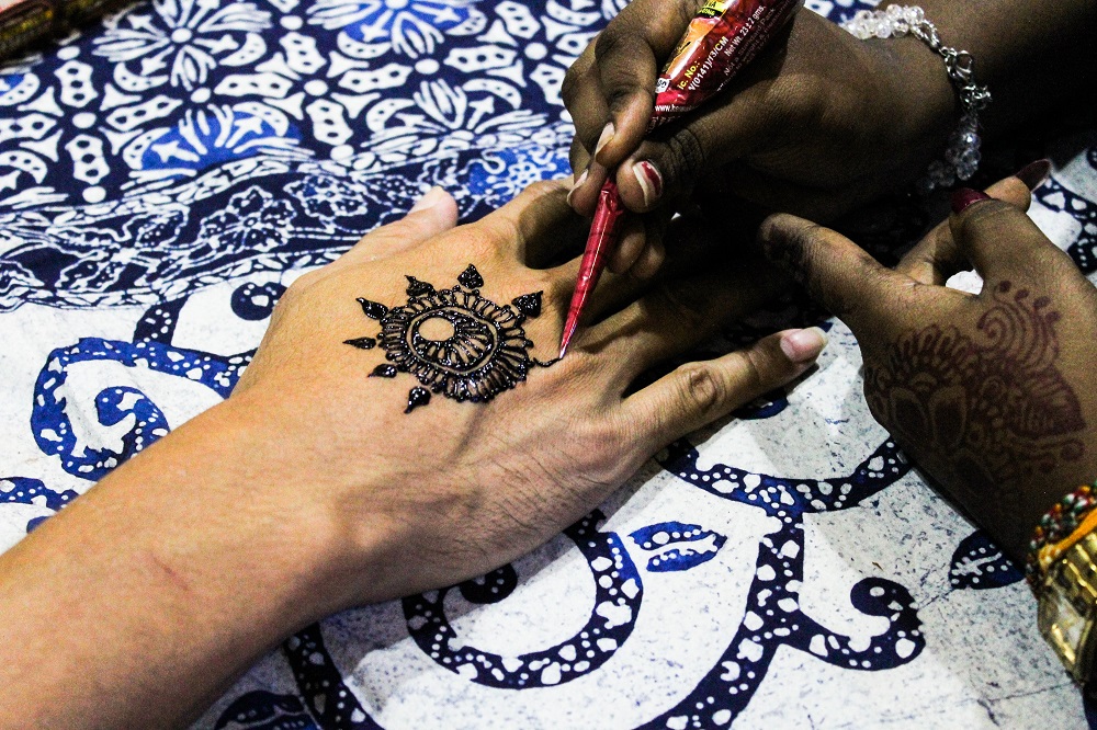 Decorative henna is painted on the hand of an exhibition visitor.