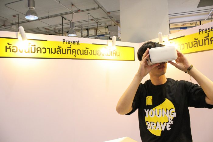 Amnesty International intern Tanawat Papaeng looks through a VR headset at different refugee homes. 