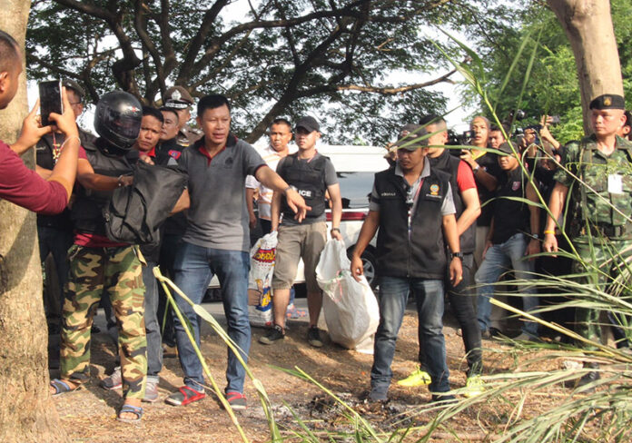 Police lead Thanakrit Prakob, in helmet, through a ‘re-enactment’ of his crime Sunday in eastern Bangkok.