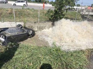A Honda rests upside down in a nearby flooded gully. Photo : JS100.com