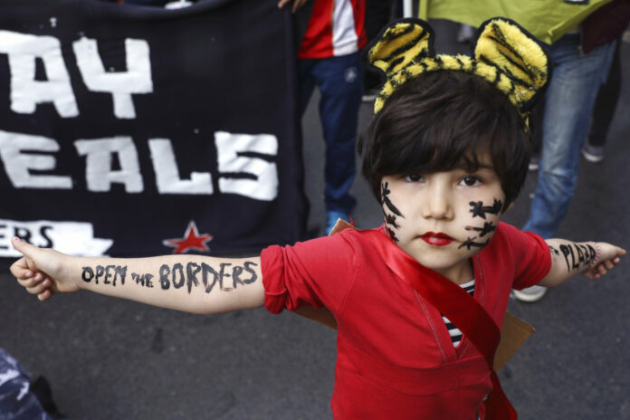 A girl poses in a March 17, 2018, file photo during a rally against the EU-Turkey deal blocking mass migration into Europe, in Athens. Photo: Yorgos Karahalis / Associated Press