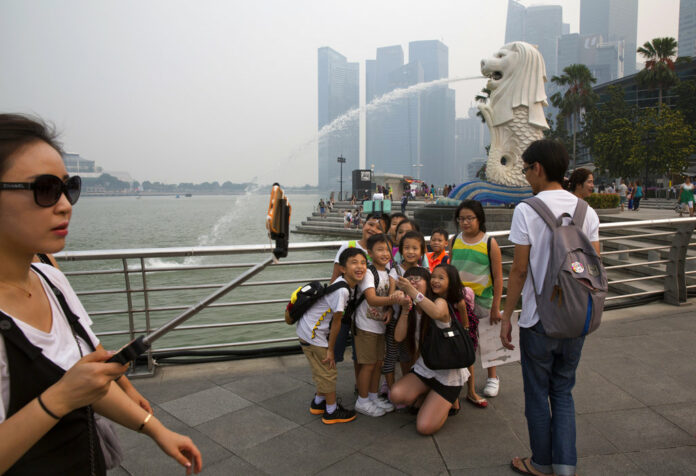Visitors pose for selfies Sept. 10 near the iconic Merlion statue in Singapore. Photo: Ng Han Guan / Associated Press