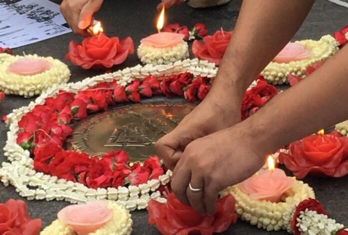 An activist lays down flowers around a plaque commemorating the 1932 revolution at Royal Plaza in Bangkok on June 24, 2016.