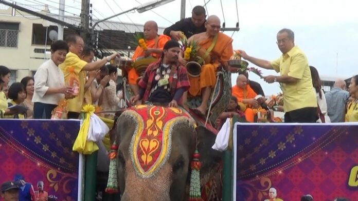 Monks mount an elephant Friday in Surin province. Photo: Matichon