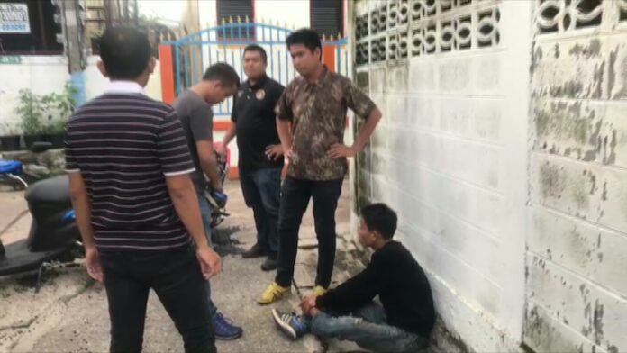 Dejdamrong Jomthank sits on the floor Tuesday during a police reenactment at Wat Nong Waeng in Khon Kaen.