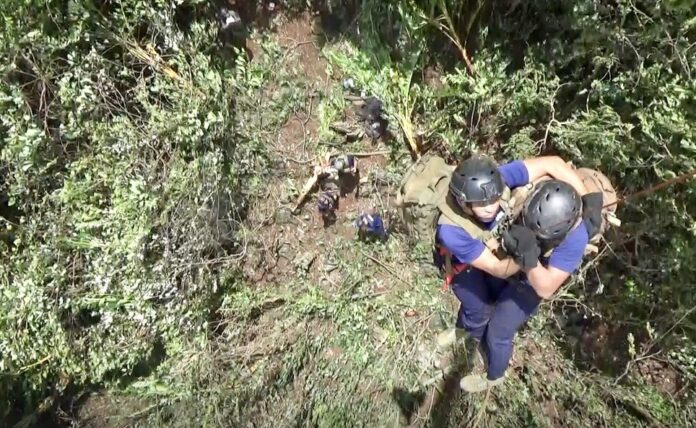 Border patrol police on Friday morning descend by rope from a helicopter onto a hill above the cave.