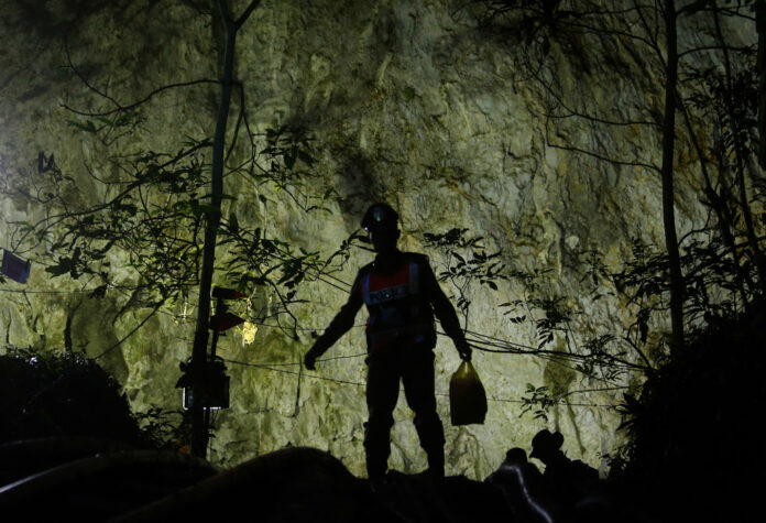 Rescuers Sunday make their way down at the entrance to a cave complex where 12 boys and their soccer coach went missing, in Mae Sai, Chiang Rai province. Photo: Sakchai Lalit / Associated Press