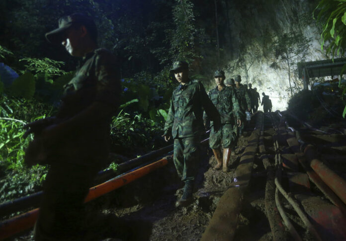 Rescuers Sunday make their way down at the entrance to a cave complex where 12 boys and their soccer coach went missing, in Mae Sai, Chiang Rai province. Photo: Sakchai Lalit / Associated Press